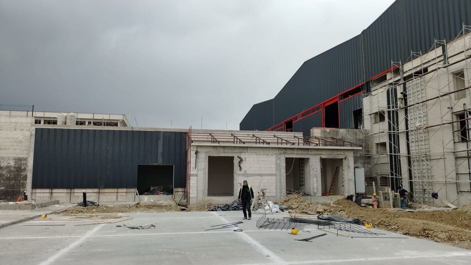 Kırmızı bant detaylı, koyu gri cepheli endüstriyel tesis